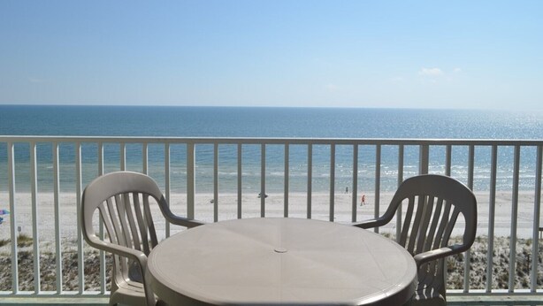 A balcony with a table and two chairs overlooking a beach. - Beautiful Renovated Gulf Front Condo! (Gulf Shores)