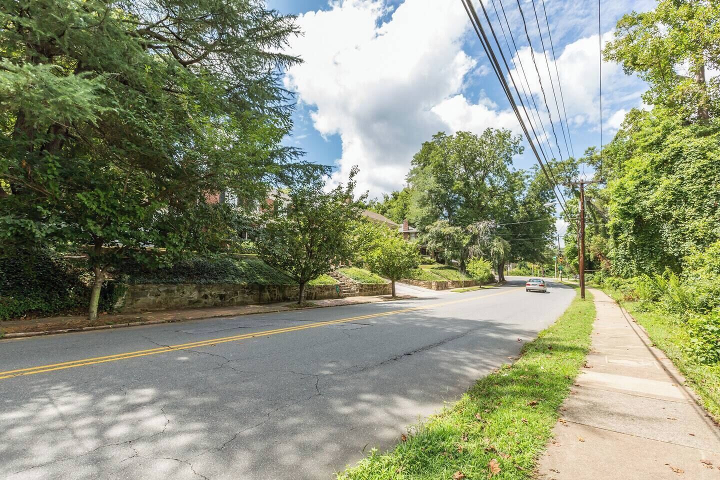A residential street with houses on both sides, a sidewalk, and a clear sky.
