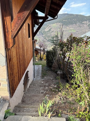 Escadaria de madeira que leva a um edifício com vista para uma paisagem montanhosa.