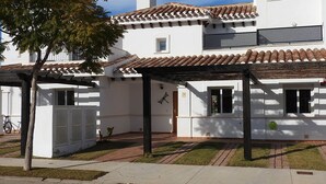 A white building with a tiled roof, a covered patio area, and a small garden. - Frontline Townhouse, Beautifully Furnished, Private Pool, Full a/c, Wi-Fi (Torre Pacheco)