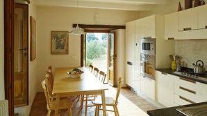 Una cocina con sillas de madera, una mesa de comedor, una estufa y armarios.