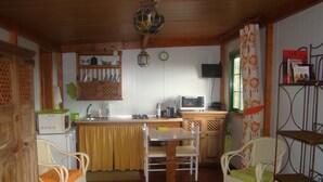 A compact kitchen with a microwave, sink, and wooden cabinets. There is a dining table with chairs and a small wooden table in the center.