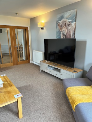 A living room with a TV, sofa, and a painting of a dog.