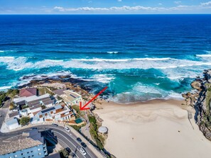 Vista aérea de una zona costera con playa, costa rocosa y edificios.