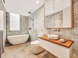 Un baño moderno con una bañera independiente, un inodoro y un tocador con lavamanos.