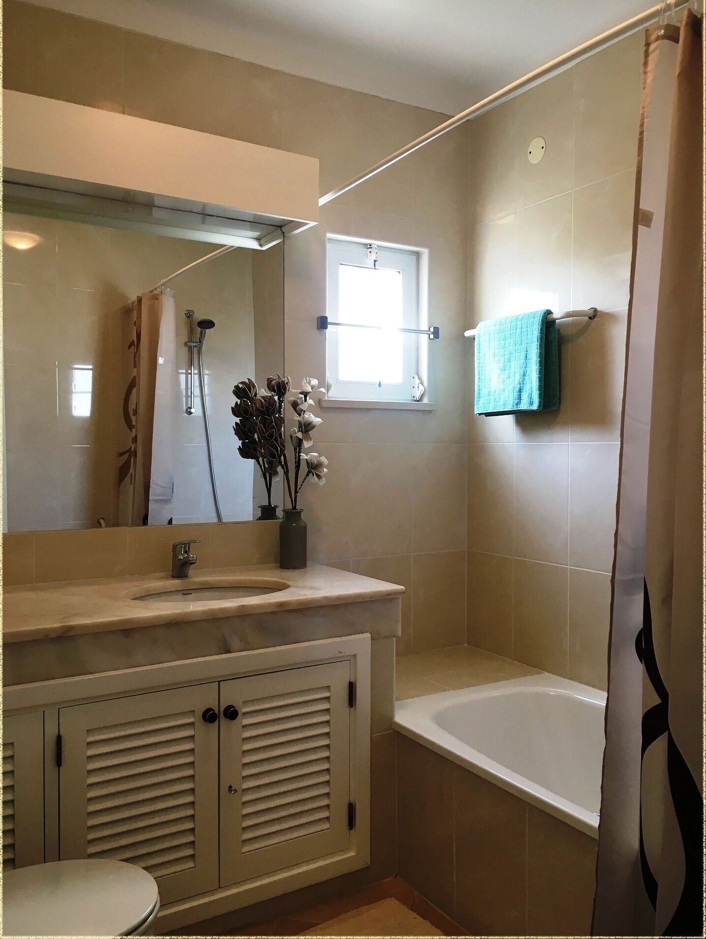A bathroom with a bathtub, a sink with a mirror, and a window.