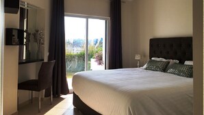 Une chambre avec un grand lit, un bureau, une chaise, un miroir et une vue sur l’extérieur.