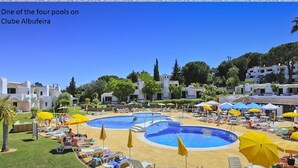 Un complexe hôtelier doté de plusieurs piscines, de chaises longues et de parasols.