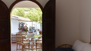 Une pièce comprenant un lit, une table avec des chaises, et une porte ouverte donnant sur un espace extérieur équipé d’une table et de chaises.