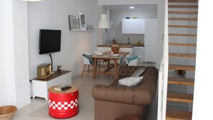 Ett modernt vardagsrum med en brun soffa, en röd pall och en matplats med ett träbord och stolar.