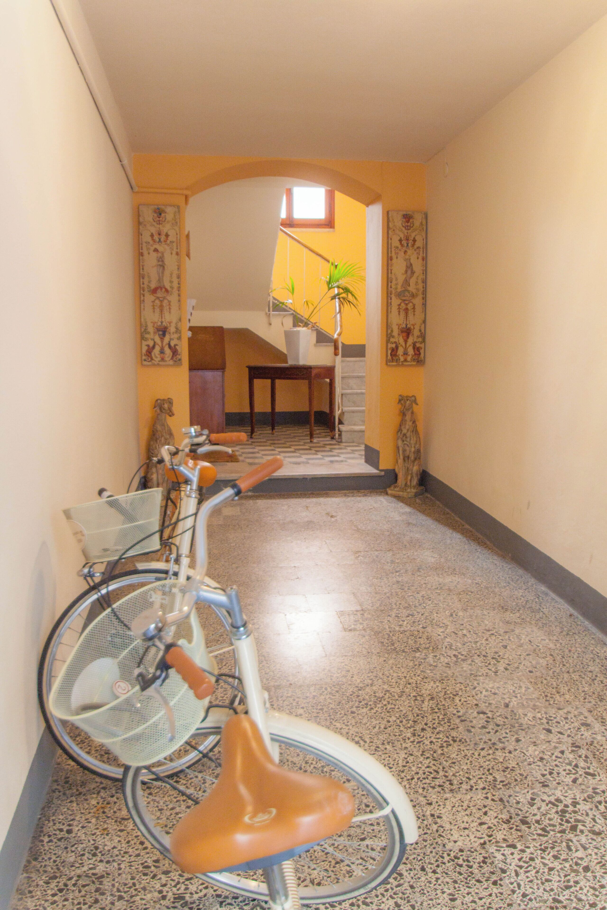 A hallway with a bicycle, a staircase, and a dining area.