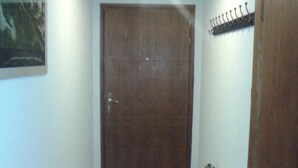 A hallway with a wooden door, a fire extinguisher, and a ceiling light fixture. - Apartment with three genuine bedrooms within 2 mins walk of the main lift (Morillon)