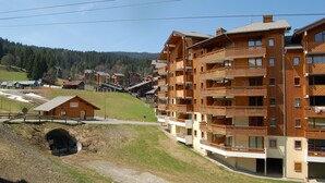 A multi-story wooden building with balconies, a ski lift, and a tunnel entrance. - Apartment with three genuine bedrooms within 2 mins walk of the main lift (Morillon)