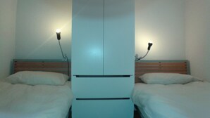 A room with two beds, each with a wooden headboard and white bedding. There are two bedside lamps on the wall. - Apartment with three genuine bedrooms within 2 mins walk of the main lift (Morillon)