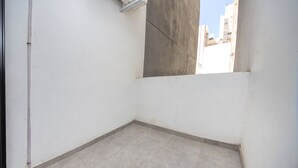 Une petite pièce vide aux murs blancs, dotée d’un sol carrelé et d’un pilier en béton.