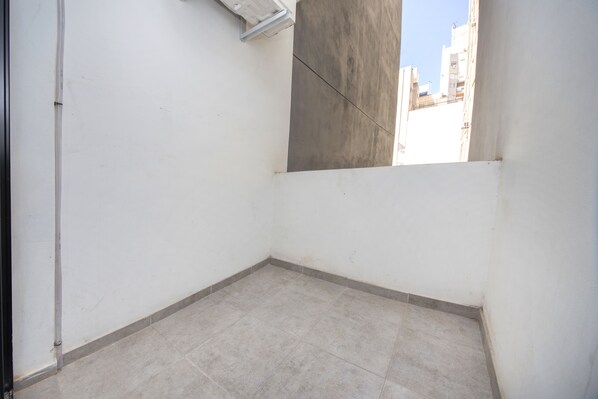 A small, empty room with white walls, a tiled floor, and a concrete pillar.