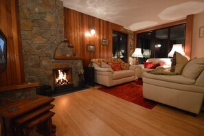 Un salón acogedor con una chimenea de piedra, dos sofás y una mesa de madera.