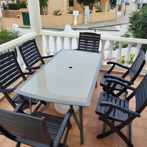 A terrace with a square table and six chairs.