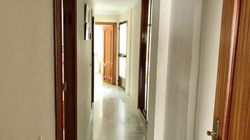 Un corridoio con porte in legno e pavimento piastrellato che conduce a una stanza luminosa.