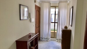 A hallway with a wooden cabinet, a door, and a window with curtains.