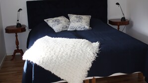 A bed with a dark headboard, two matching pillows, and a white throw blanket.