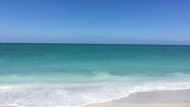 A beach with clear turquoise water and a sandy shore.