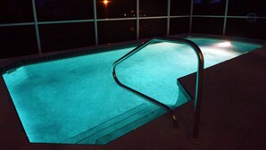 A swimming pool with a glass enclosure and a metal ladder.