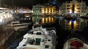 A marina at night with boats docked, a well-lit building with multiple balconies, and calm water reflecting the lights. - 4 Bedroom Villa in Benalmadena Pueblo with pool and Magnificent Panoramic views (Benalmádena)