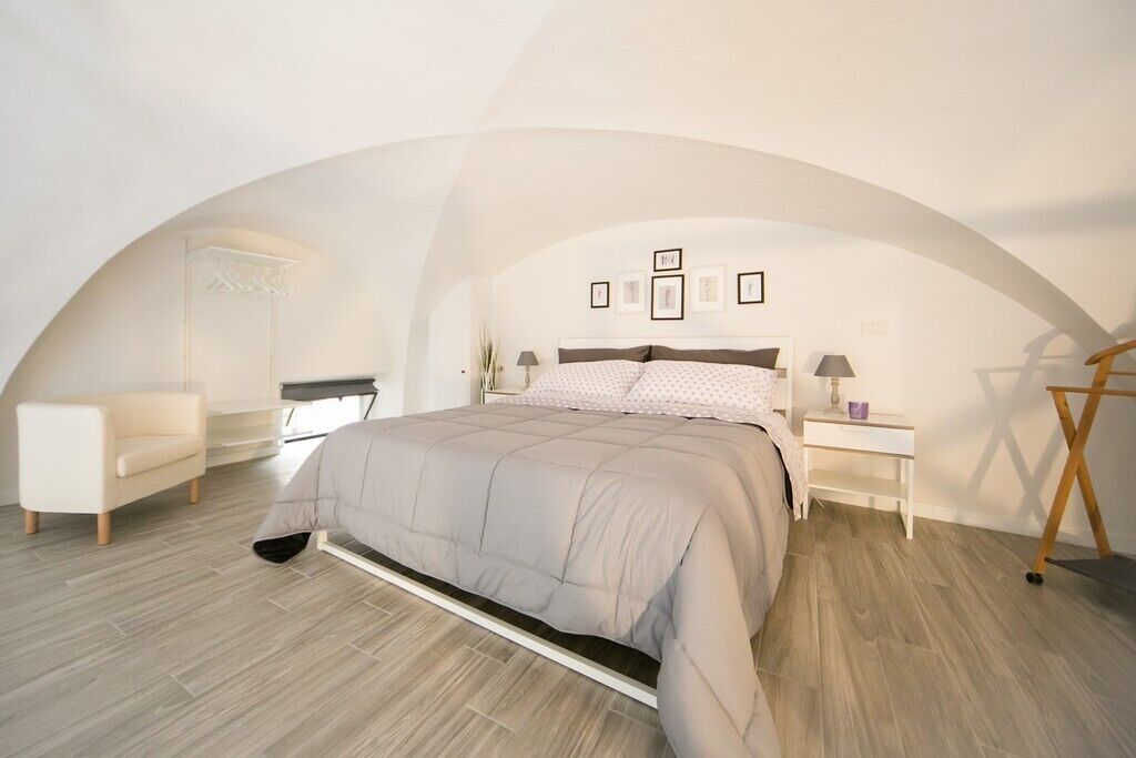 Un dormitorio con una cama, una mesita de noche, una silla y un armario.