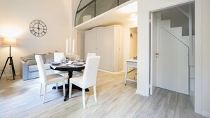 A dining area with a round table, white chairs, and a clock on the wall.