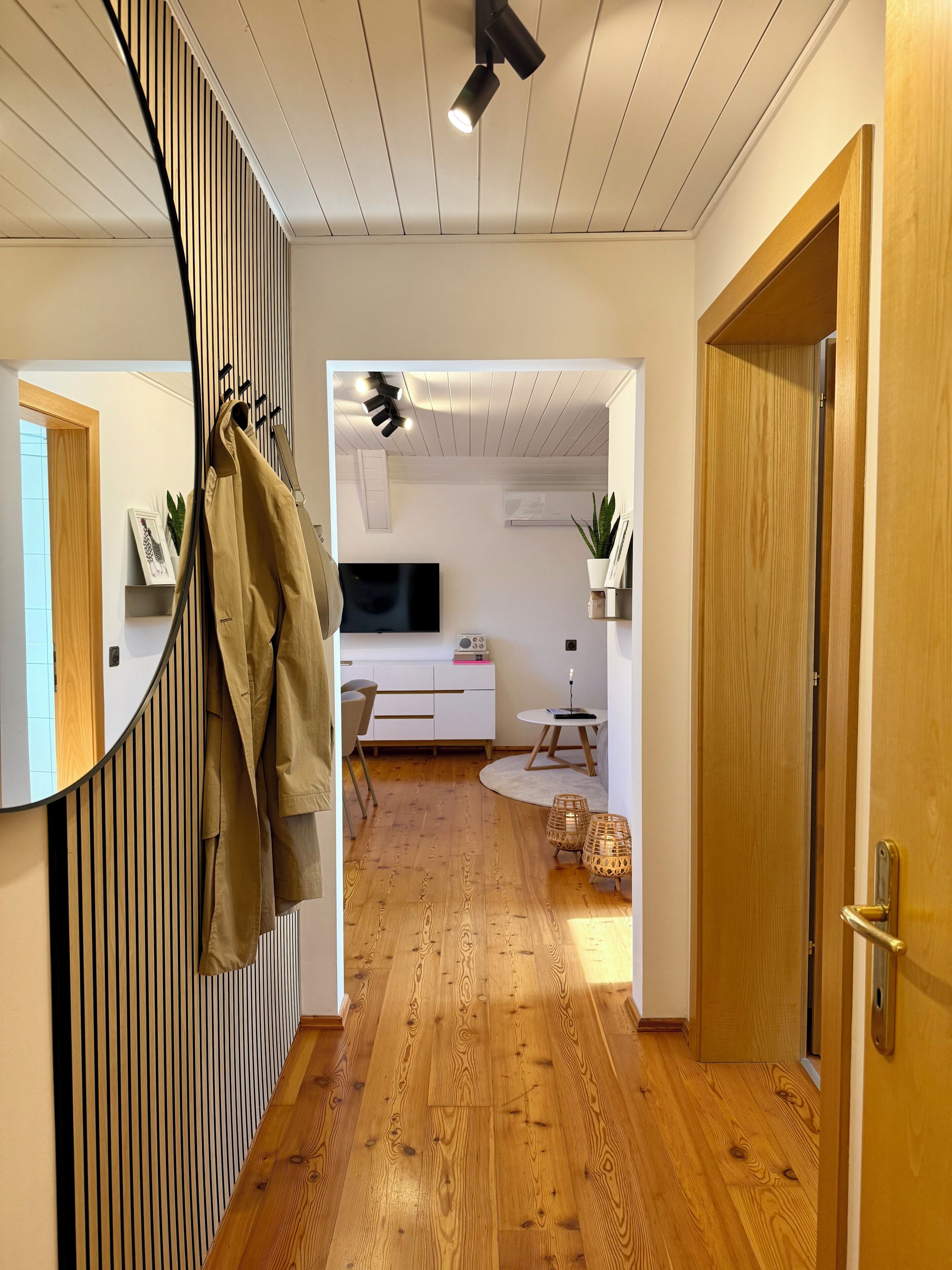 Ein modernes Interieur mit Holzboden, einer Spiegelwand und einer Decke mit Einbaustrahlern.