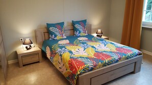 A bedroom with a bed, two nightstands, a lamp, and a window with curtains.