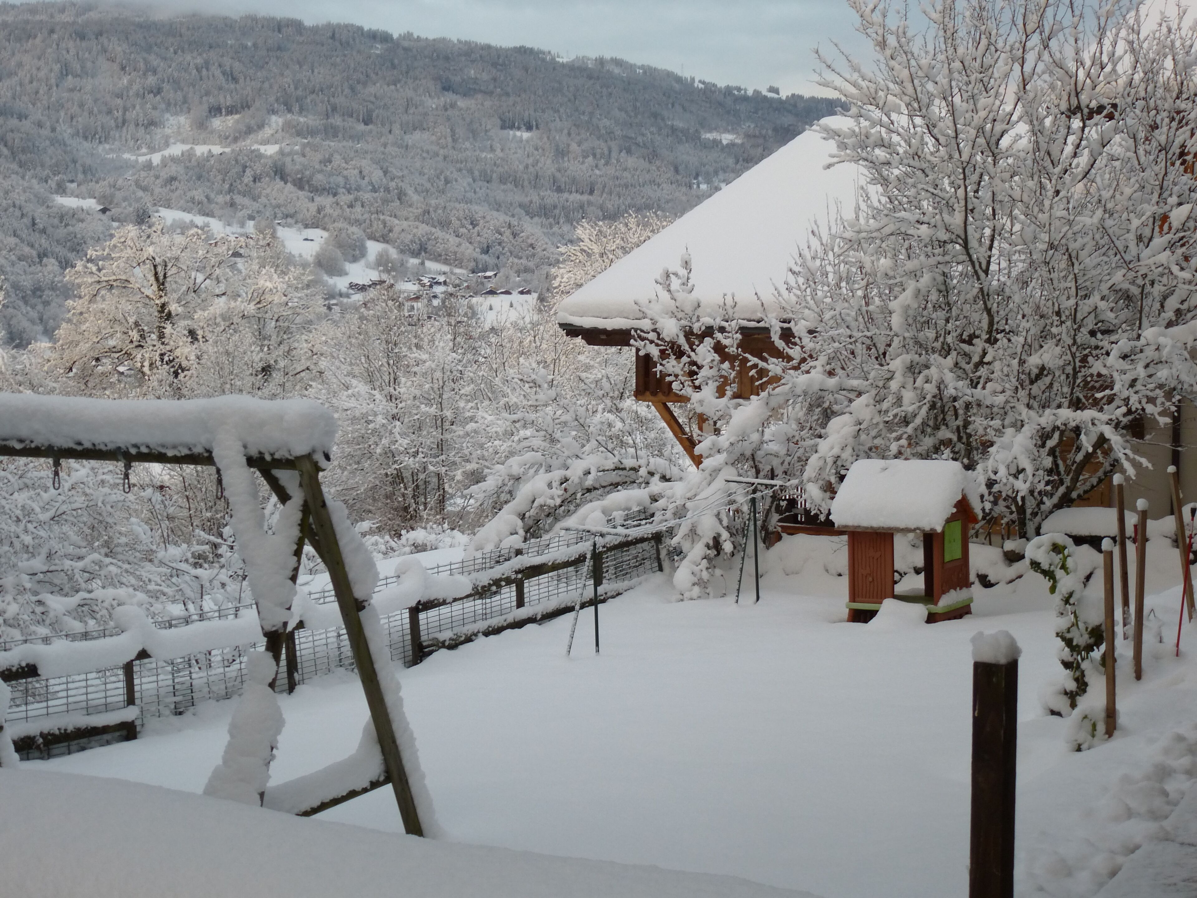 Schneeverdeckte Landschaft mit Holzgebäuden und einem eingezäunten Bereich.