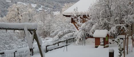 A snow-covered landscape with a wooden structure and a fenced area.