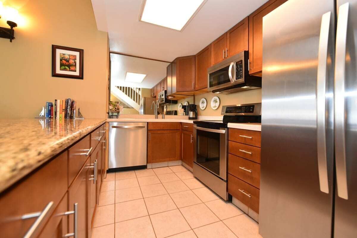 Una cocina moderna con electrodomésticos de acero inoxidable, armarios de madera y piso de baldosas.