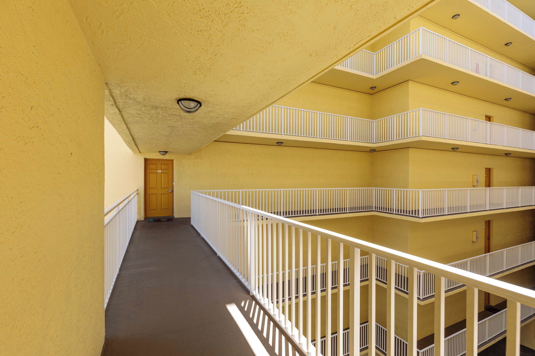 Un couloir à plusieurs niveaux, doté de rampes blanches et d’un mur jaune.