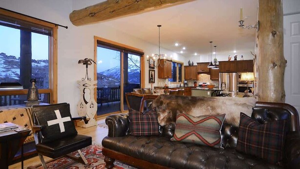 Un salon chaleureux avec un canapé en cuir, un chien et une vue sur la cuisine.