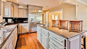 A kitchen with white cabinetry, a stainless steel refrigerator, granite countertops, and wooden flooring. - Summer Sun - Magnificent Hollywood Hills HtdPool Residence in Celebrity Enclave (Los Angeles)