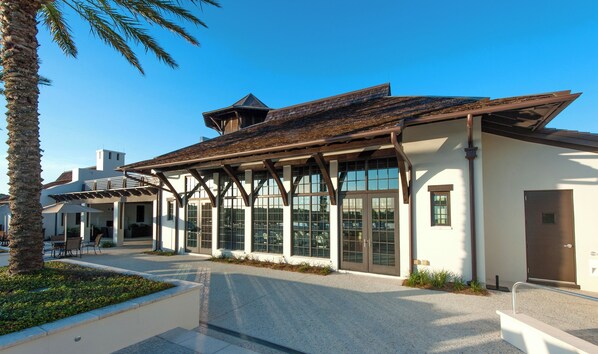 A building with large windows, a covered patio, and a palm tree.