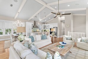 A spacious living room with a white sofa, a coffee table, and a dining area with a chandelier. - ☀️Infinity Pool-NatureTrail-30A-Day Is Done (Santa Rosa Beach)
