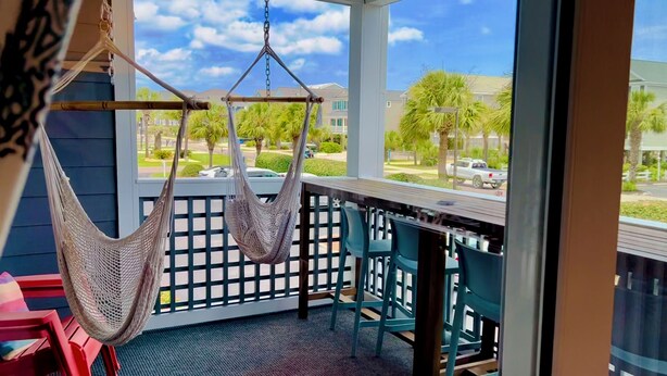 A balcony with a hammock, chairs, and a view of a residential area. - Modern, Completely Renovated 2 bdrm 2 bath Ocean View (Surfside Beach)