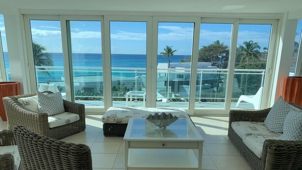 A spacious balcony with wicker furniture, a glass-top table, and a view of the ocean. - NEW Amazing Ocean View - 301C (boca chica)