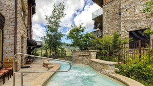 A spa area with a hot tub, stone walls, and outdoor seating.