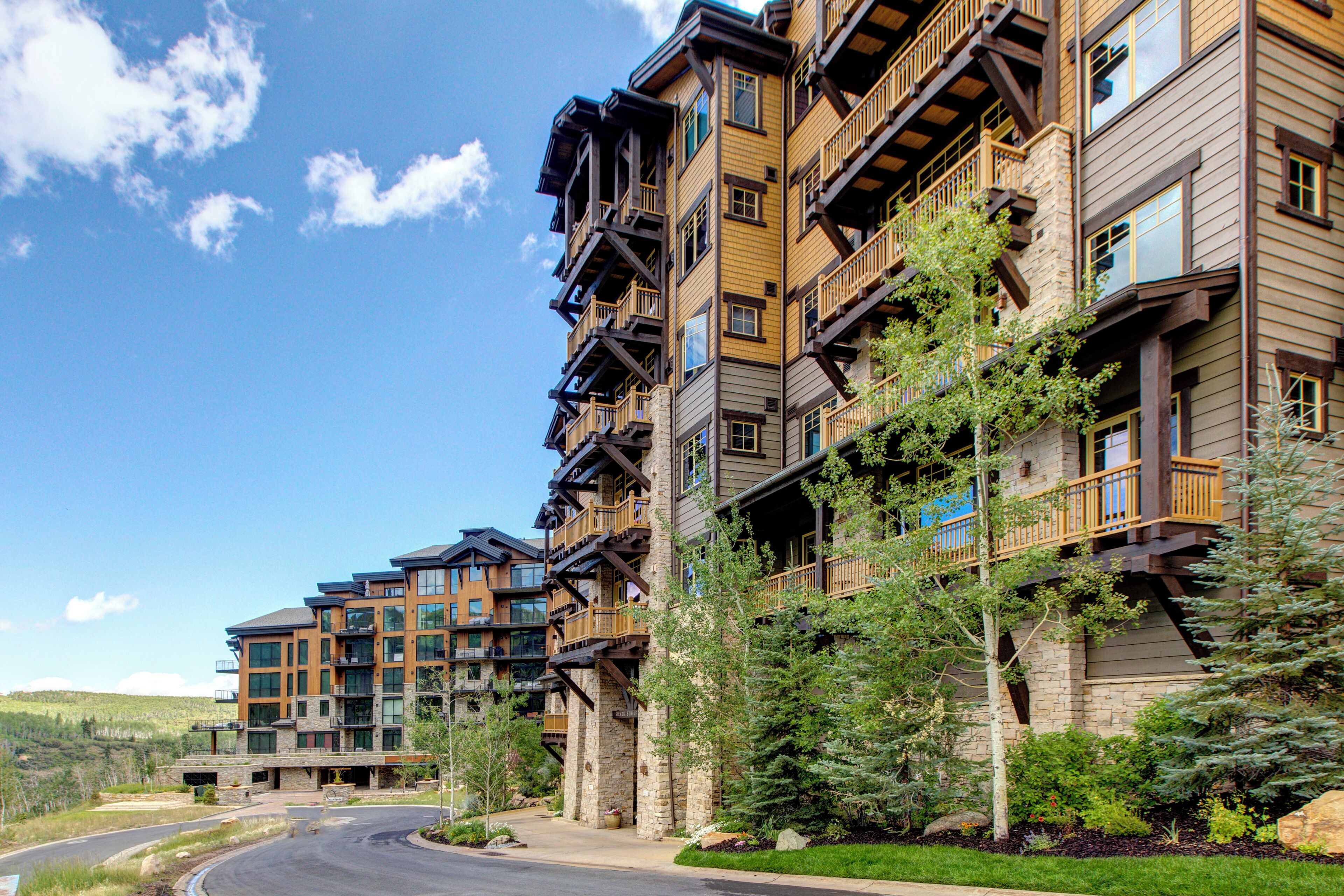 A multi-story hotel with balconies, large windows, and a landscaped driveway.
