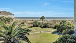 A beachfront property with a view of the ocean, a grassy lawn, and palm trees. - Award-Winning Resort Amenities | Summerhouse 205 (Isle of Palms)