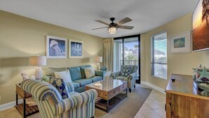 A living room with a sofa, armchairs, a coffee table, and a ceiling fan. - Award-Winning Resort Amenities | Summerhouse 205 (Isle of Palms)
