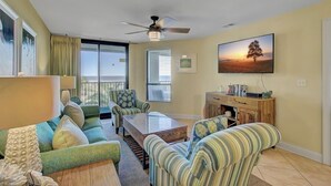 A living room with a sofa set, a coffee table, a TV mounted on the wall, and a ceiling fan. - Award-Winning Resort Amenities | Summerhouse 205 (Isle of Palms)