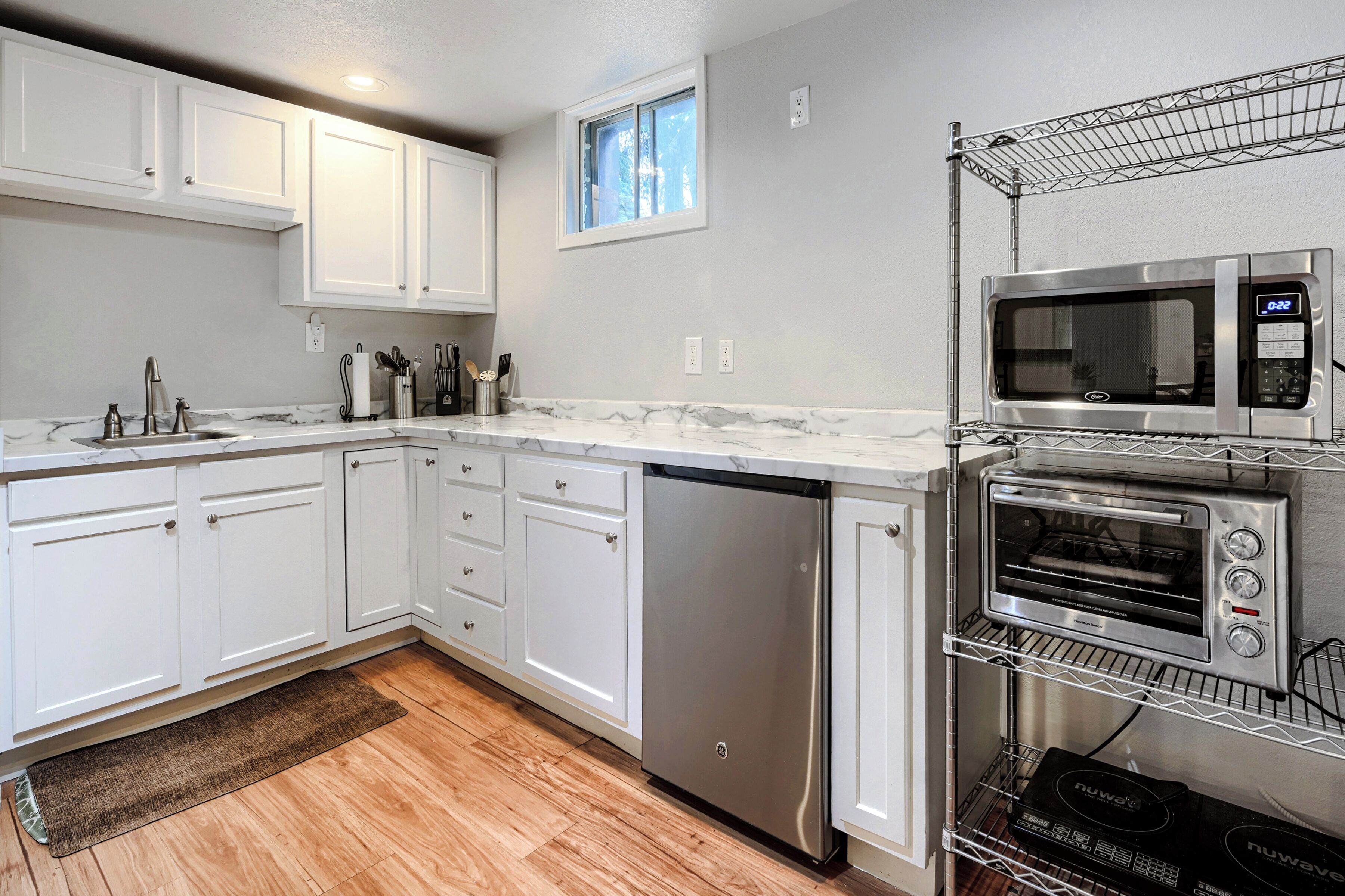 A kitchen with white cabinets, a stainless steel dishwasher, a microwave, and a built-in oven.
