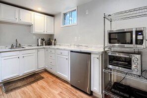 A kitchen with white cabinets, a stainless steel dishwasher, a microwave, and a built-in oven.