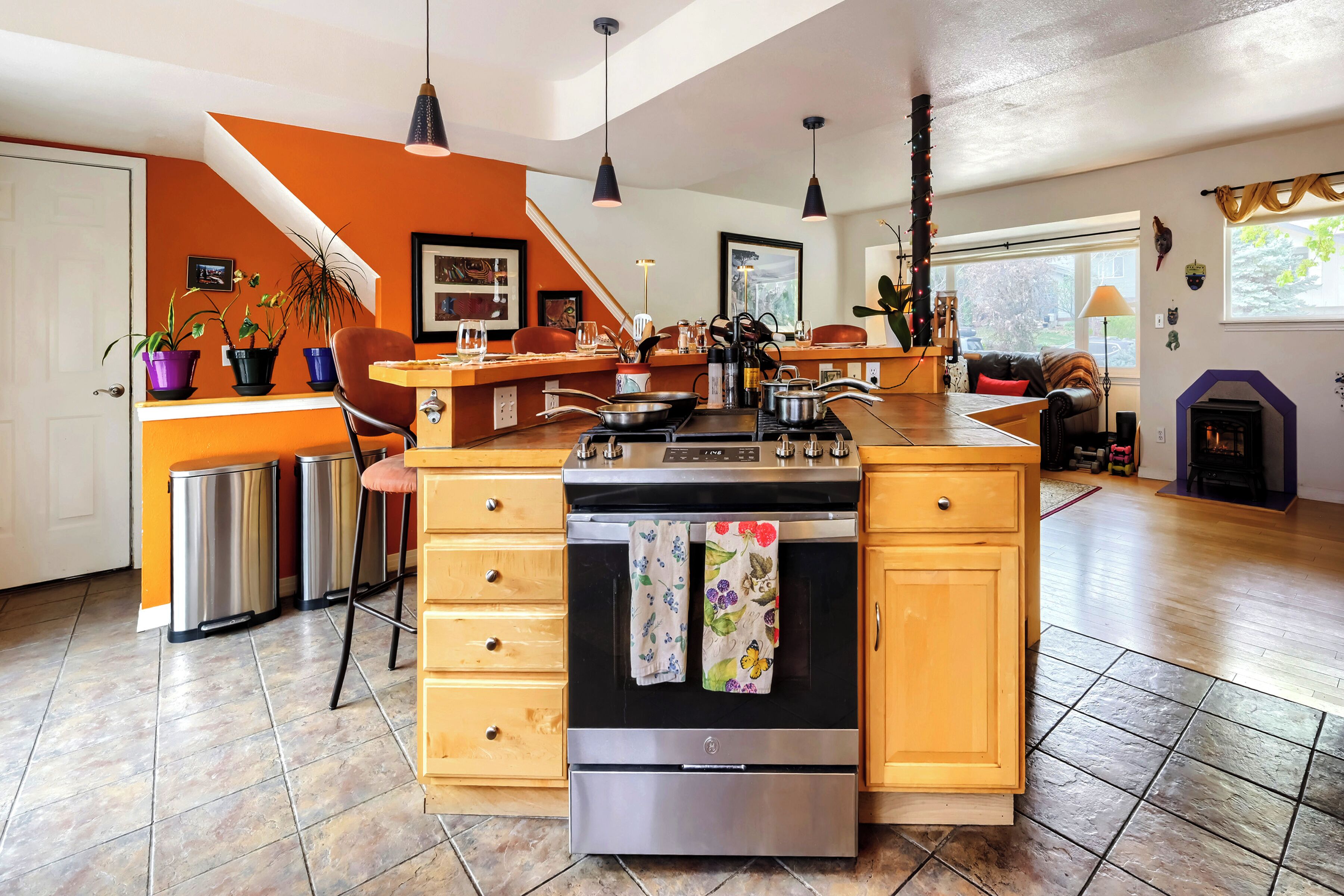 A kitchen with a central island, stainless steel appliances, wooden cabinets, and a dining area with chairs.